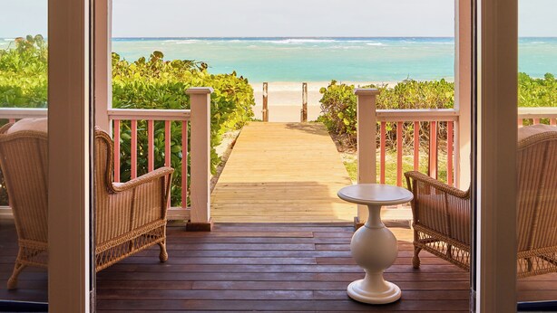 A wooden deck with wicker furniture and a view of the ocean. - Coral Sands Inn & Cottages (Dunmore Town)