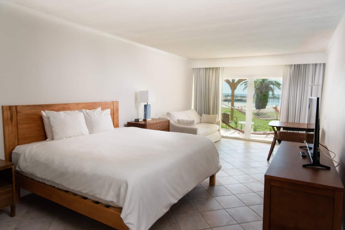Habitación de hotel con una cama grande, un escritorio, una silla y vistas al exterior.