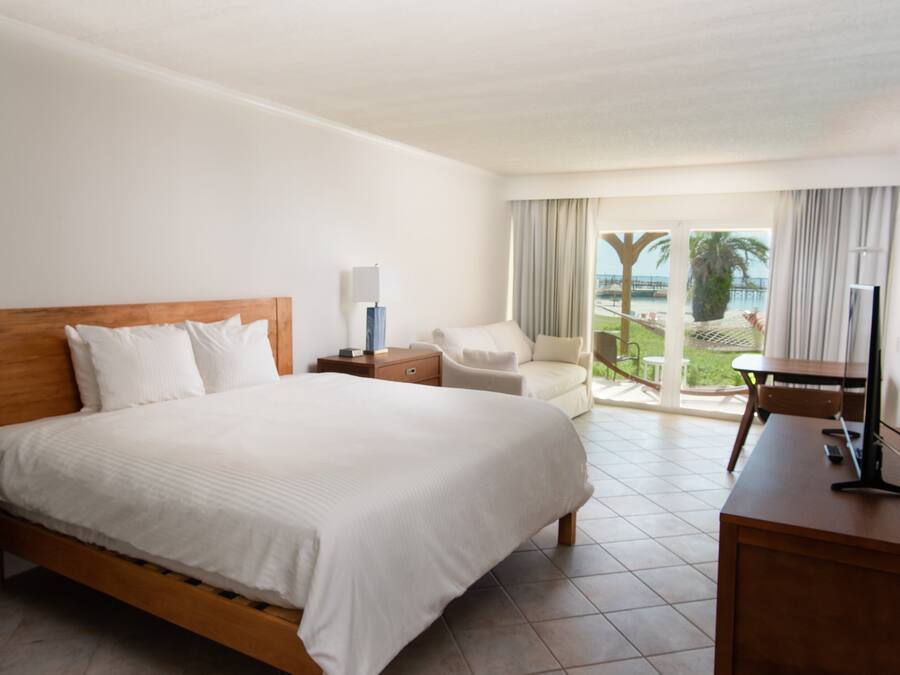 A hotel room with a large bed, a desk, a chair, and a view of the outdoors.