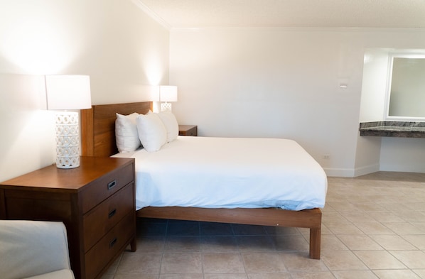 A bedroom with a wooden bed, white bedding, two bedside lamps, and a nightstand. - Abaco Beach Resort and Boat Harbour Marina (Marsh Harbour)