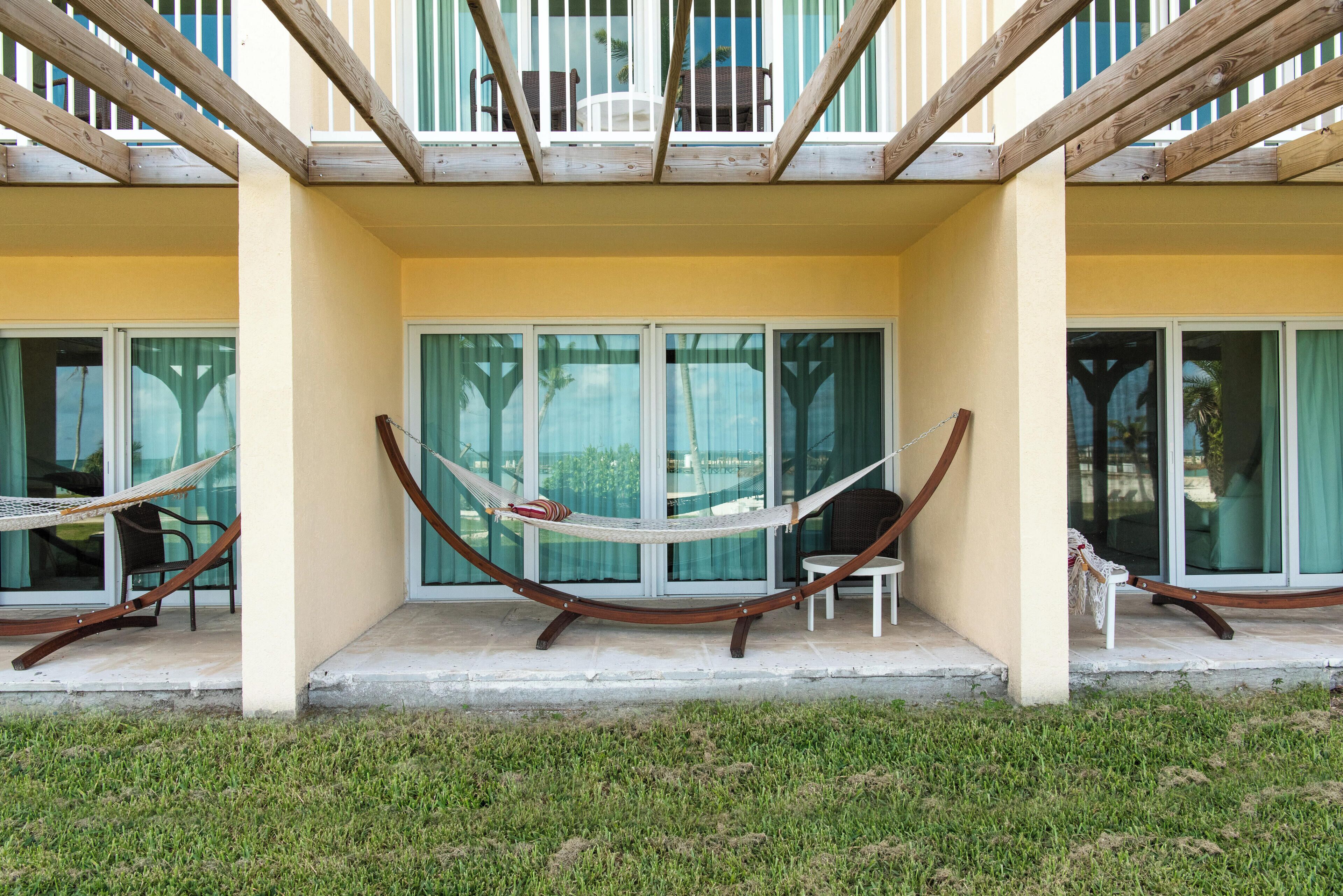A balcony with a hammock, glass doors, and a view of the surrounding area.
