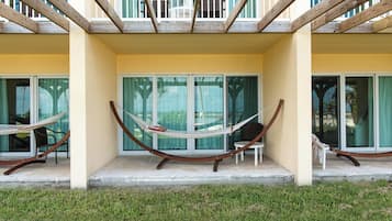 A balcony with a hammock, glass doors, and a view of the surrounding area.