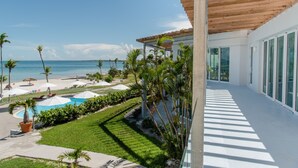 Un complexe hôtelier moderne doté d’une piscine, de palmiers et offrant une vue sur la plage.