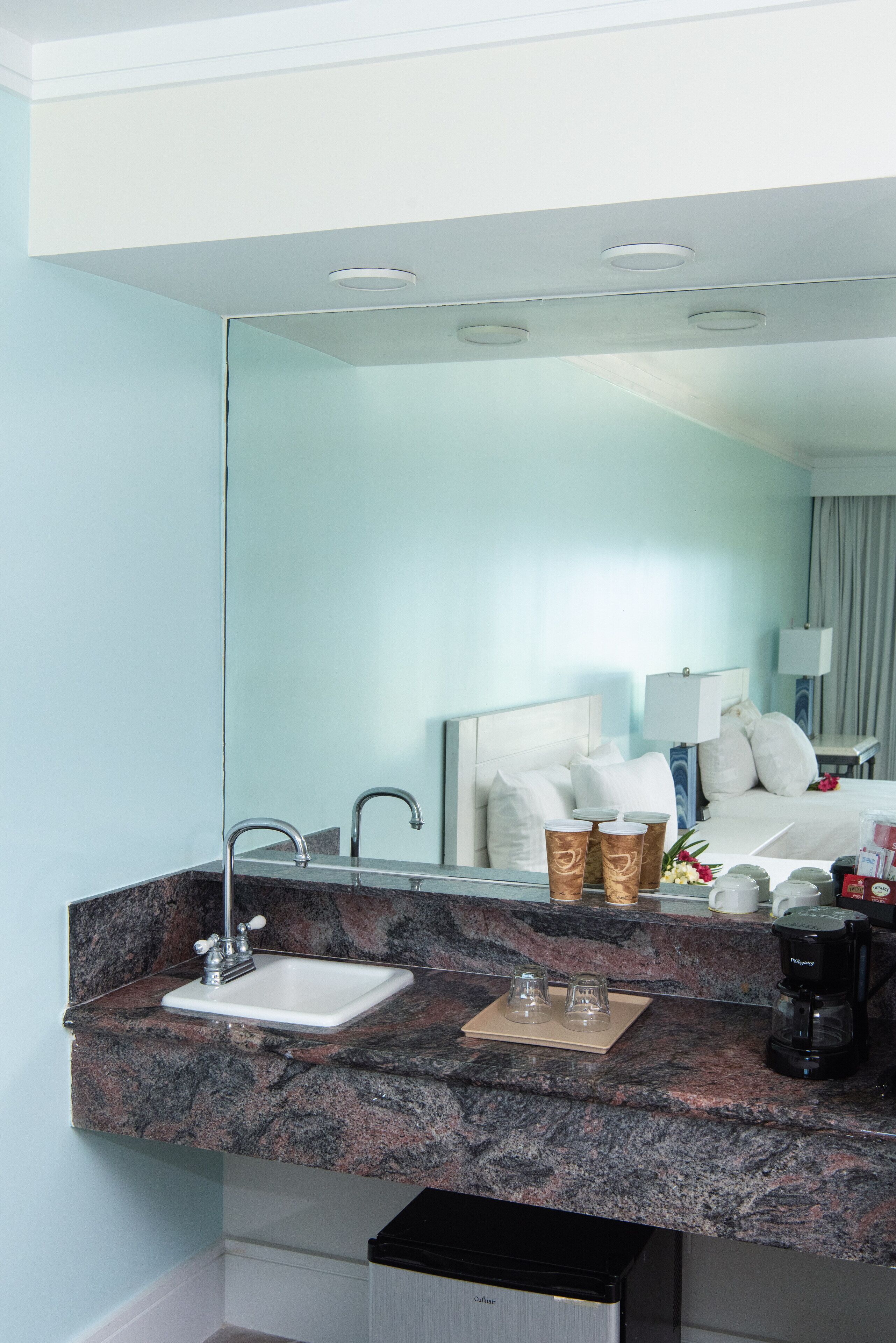 Un baño de hotel con encimera de granito, lavamanos y espejo.