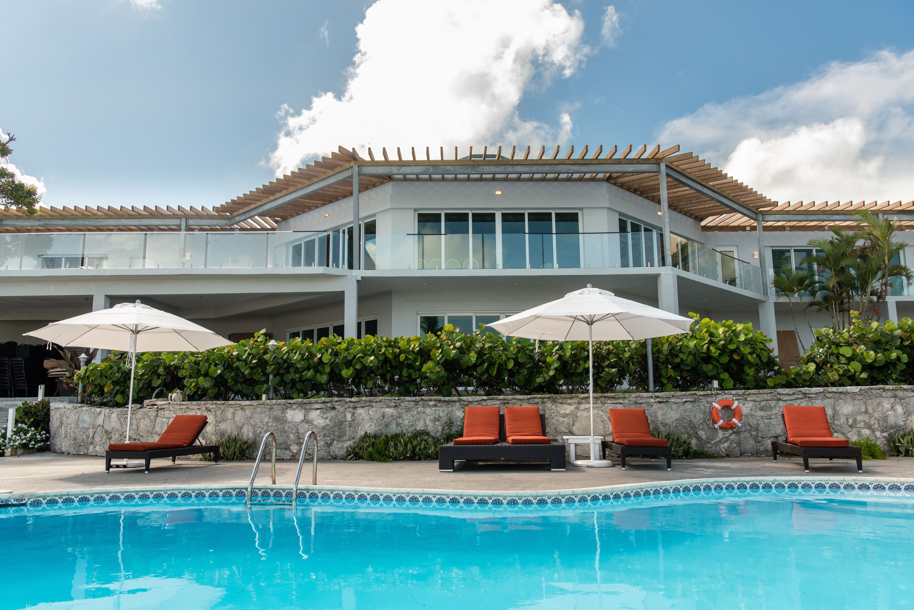 Un hotel moderno con piscina, zona de estar exterior y pared de piedra.