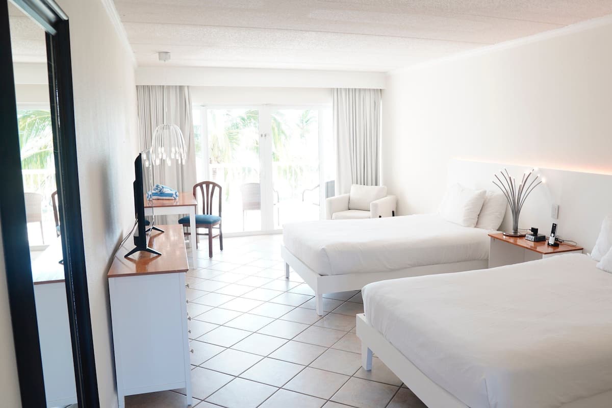 Habitación de hotel con dos camas, un escritorio, una silla y vistas al exterior.
