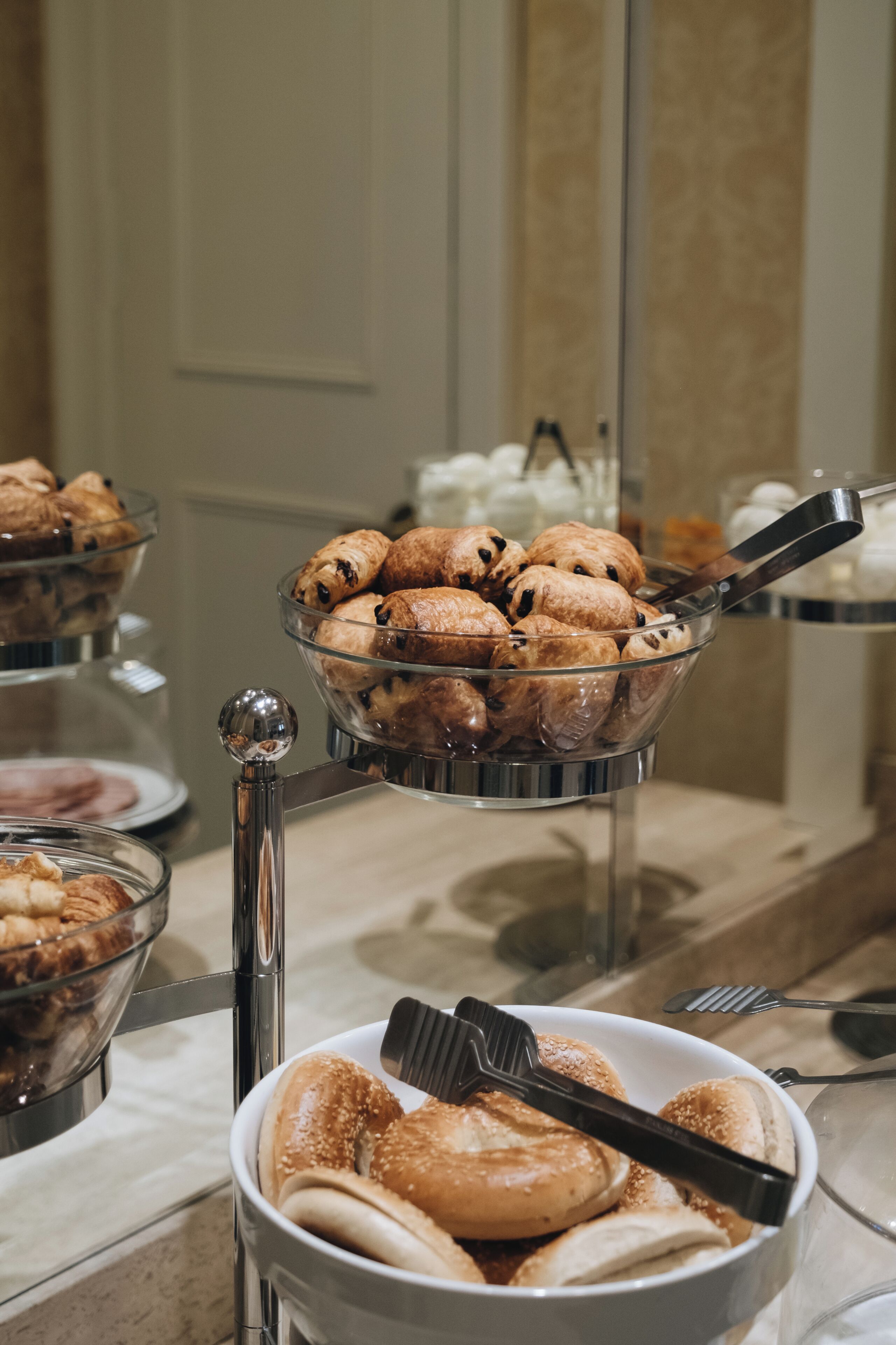 A buffet with various baked goods, including pastries and bread, arranged on a buffet stand.