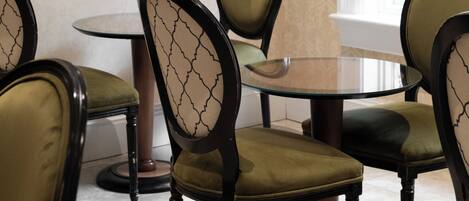 A dining area with round tables and chairs, a mirror on the wall, and a window with a view.