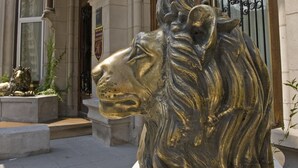 A bronze lion statue in front of a building with a sign that reads "CHATEAU VERSAILLES." - Chateau Versailles (Montreal)