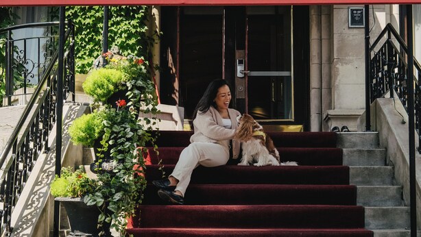 A red awning with 'CHÂTEAU VERSAILLES' text, a staircase with red carpet, and a building facade with greenery. - Chateau Versailles (Montreal)