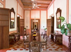 A traditional dining room with a long table, chairs, and a ceiling fan.