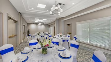 A conference room with round tables, chairs, and a chandelier.