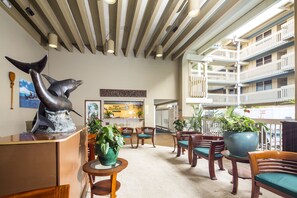 Guests enter a spacious lobby with a high ceiling, featuring exposed beams and a unique whale sculpture.