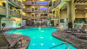A multi-level hotel with a swimming pool, outdoor seating, and multiple balconies.
