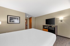 A hotel room with a large bed, a flat-screen TV, a minibar, and a framed picture on the wall. - Best Western Cascade Inn & Suites (Wood Village)