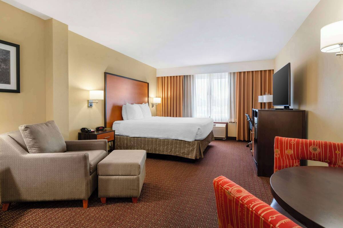 Une chambre d’hôtel avec un lit, un canapé, une petite table et un téléviseur.