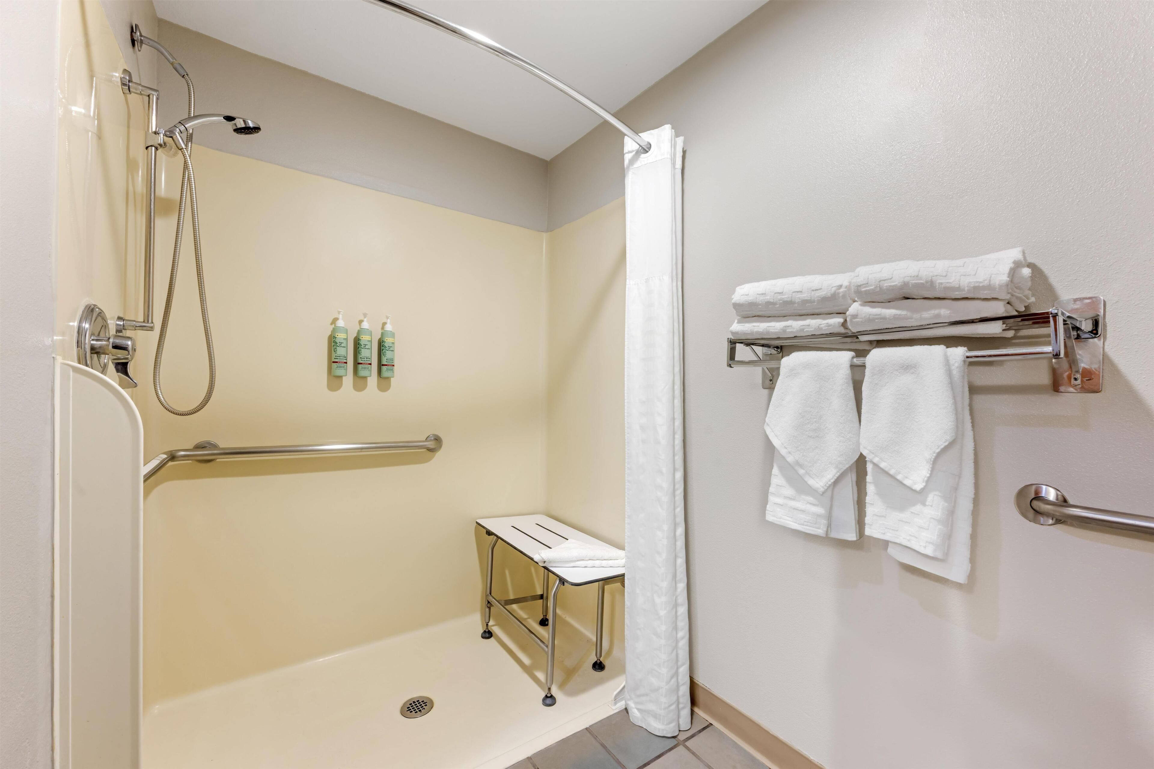 A bathroom with a shower, a hand dryer, and a towel rack.