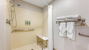 A bathroom with a shower, a hand dryer, and a towel rack.