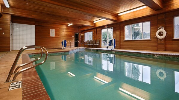 A wooden interior with a swimming pool, a lifebuoy, and a chair by the pool.