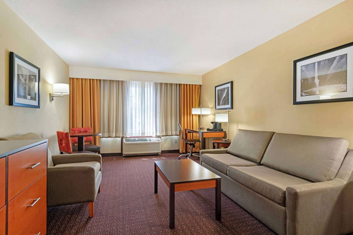 Une chambre d’hôtel avec un canapé, un fauteuil, une table, un bureau et un lit.