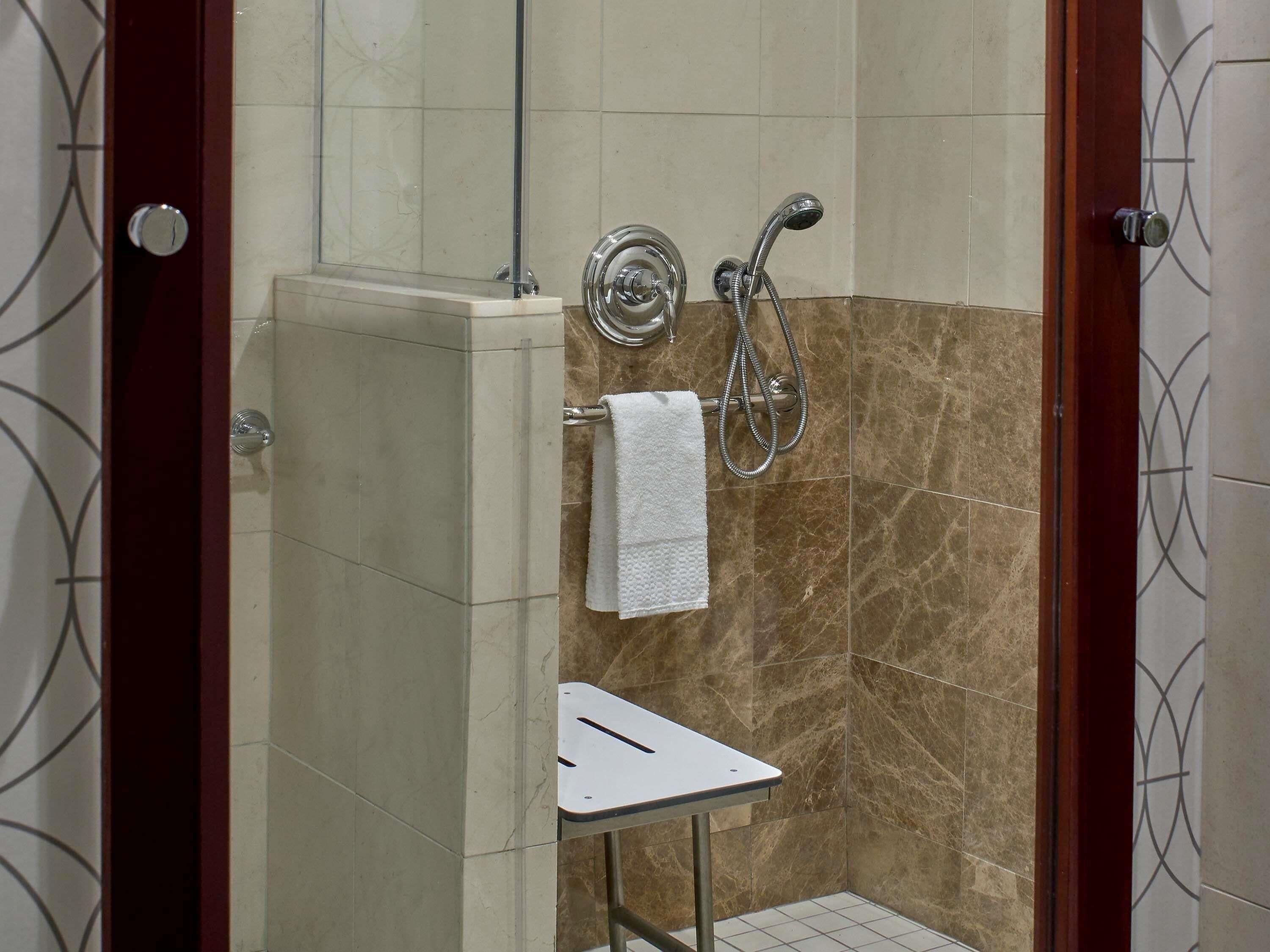 Un espace douche doté d’une porte en verre, d’un porte-serviettes et d’une petite table.