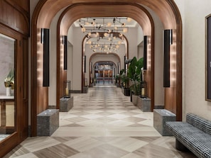 A spacious lobby with a checkered floor, wooden arches, and a modern chandelier.