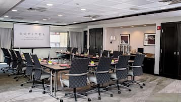 A conference room with a whiteboard, multiple chairs, a table with water bottles, and a projector screen.