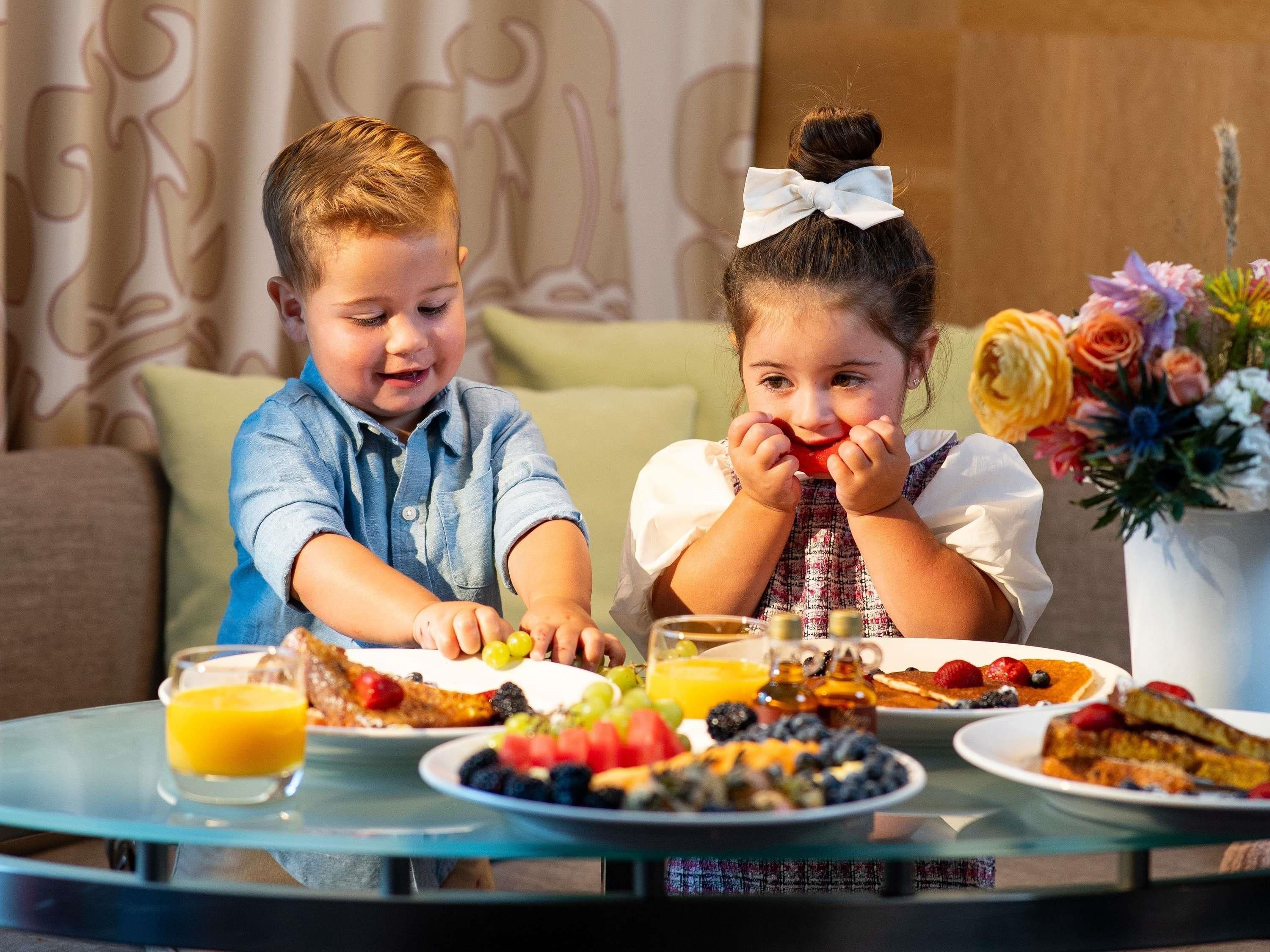 Dos niños sentados a la mesa desayunando.