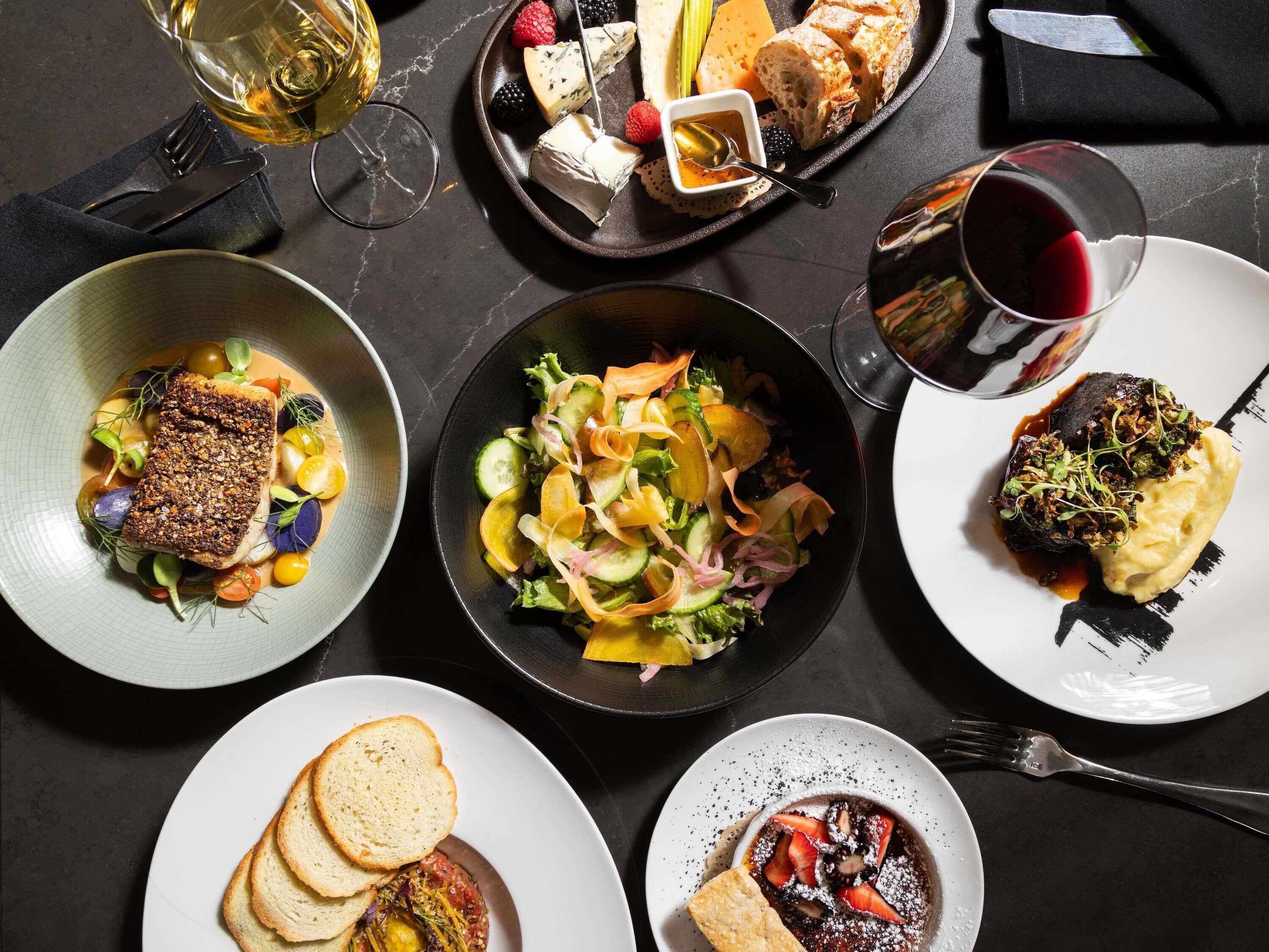 A variety of dishes on a table, including a fish dish, a salad, and a dessert.