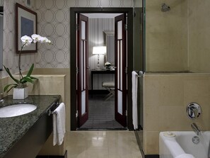 A hotel bathroom with a sink, mirror, and bathtub.
