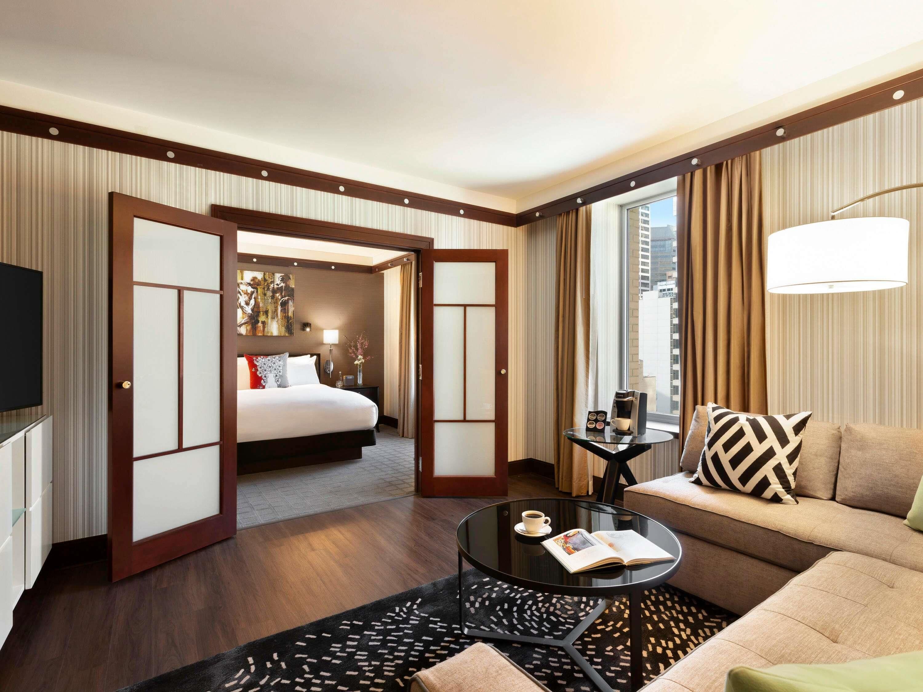 A hotel room with a bed, a sofa, a coffee table, and a TV.
