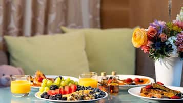 A breakfast table with plates of food, glasses of orange juice, and a vase of flowers.