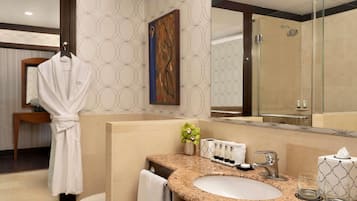 A modern bathroom with a granite countertop, a white sink, and a glass shower enclosure.