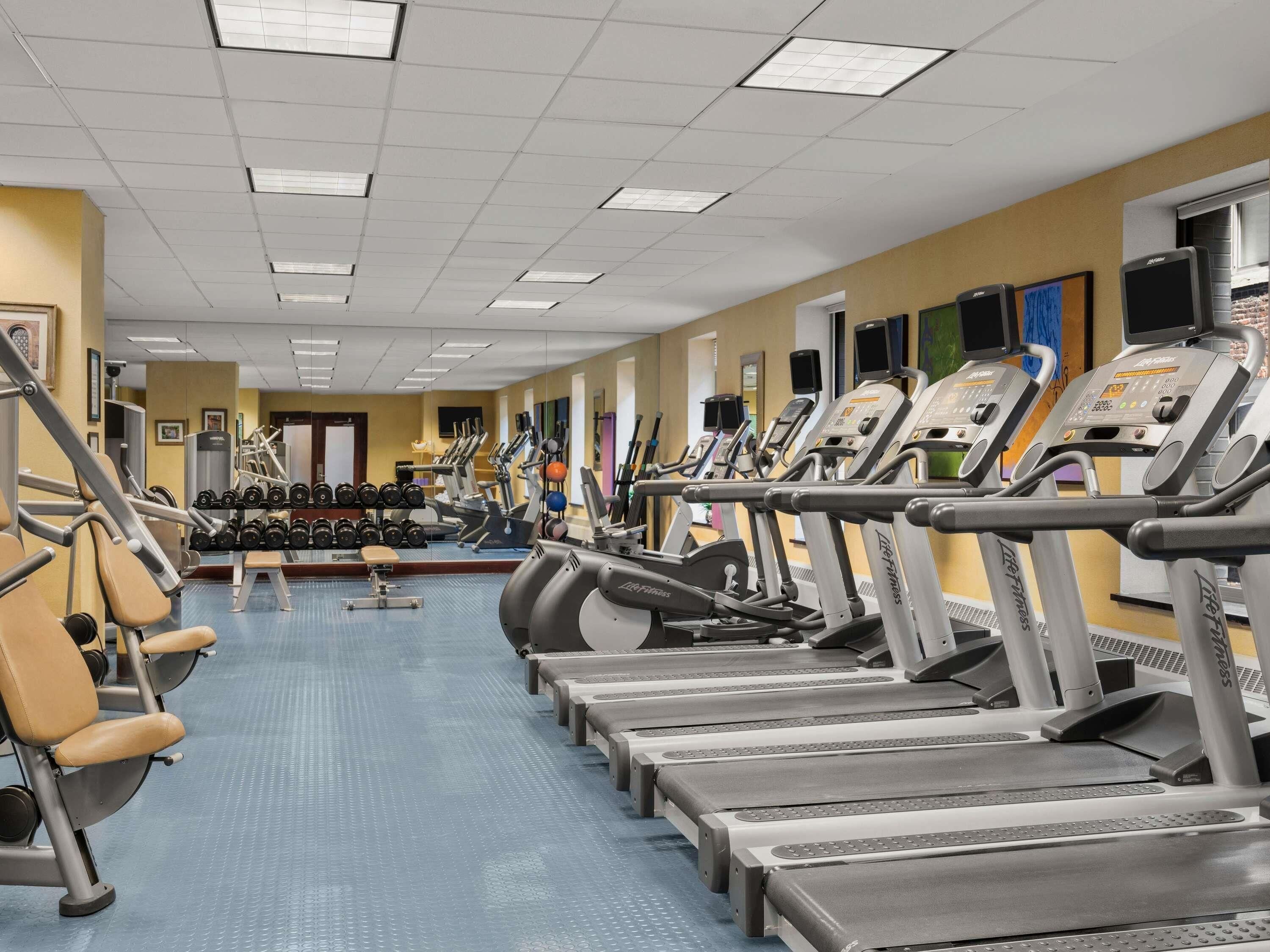 Una sala de gimnàstica amb cintes de córrer, aparells de musculació i pèses.