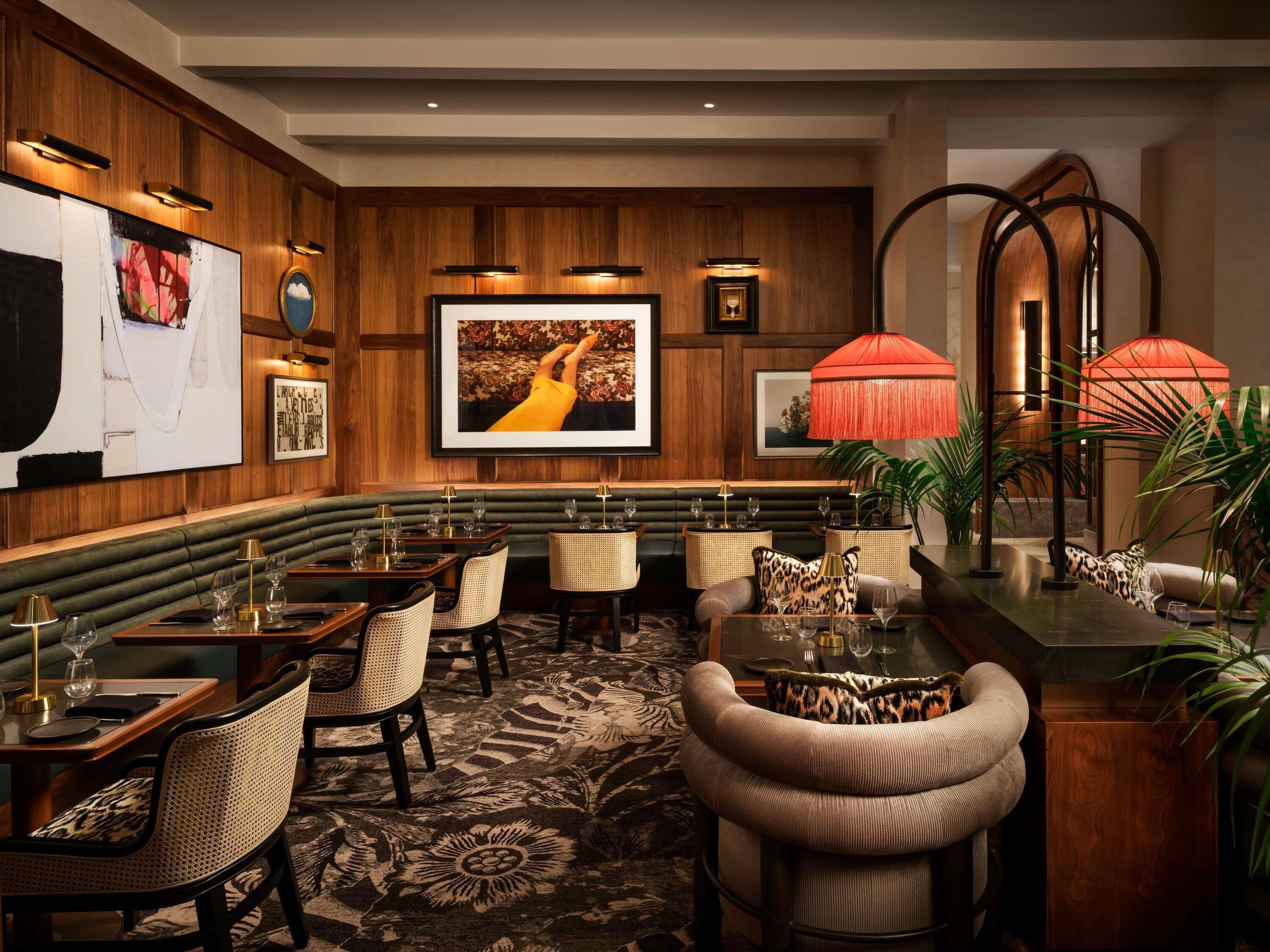 A restaurant with wooden paneling, framed artwork, and a central seating area with tables and chairs.