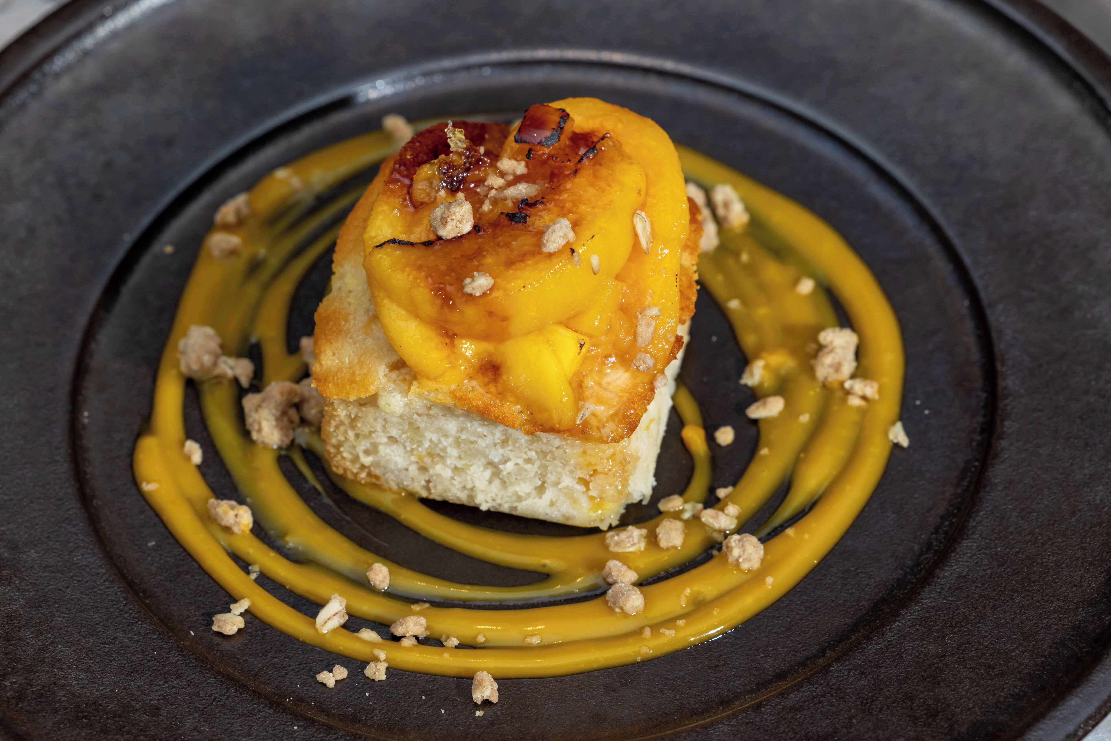 A dessert on a plate with a caramel drizzle and crumbled topping.