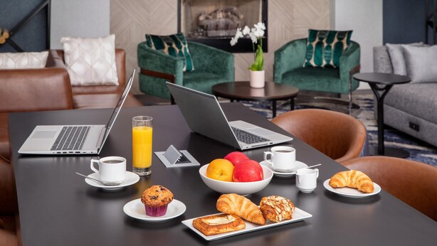Une table à manger avec des aliments pour le petit-déjeuner, deux ordinateurs portables et une tasse de café.