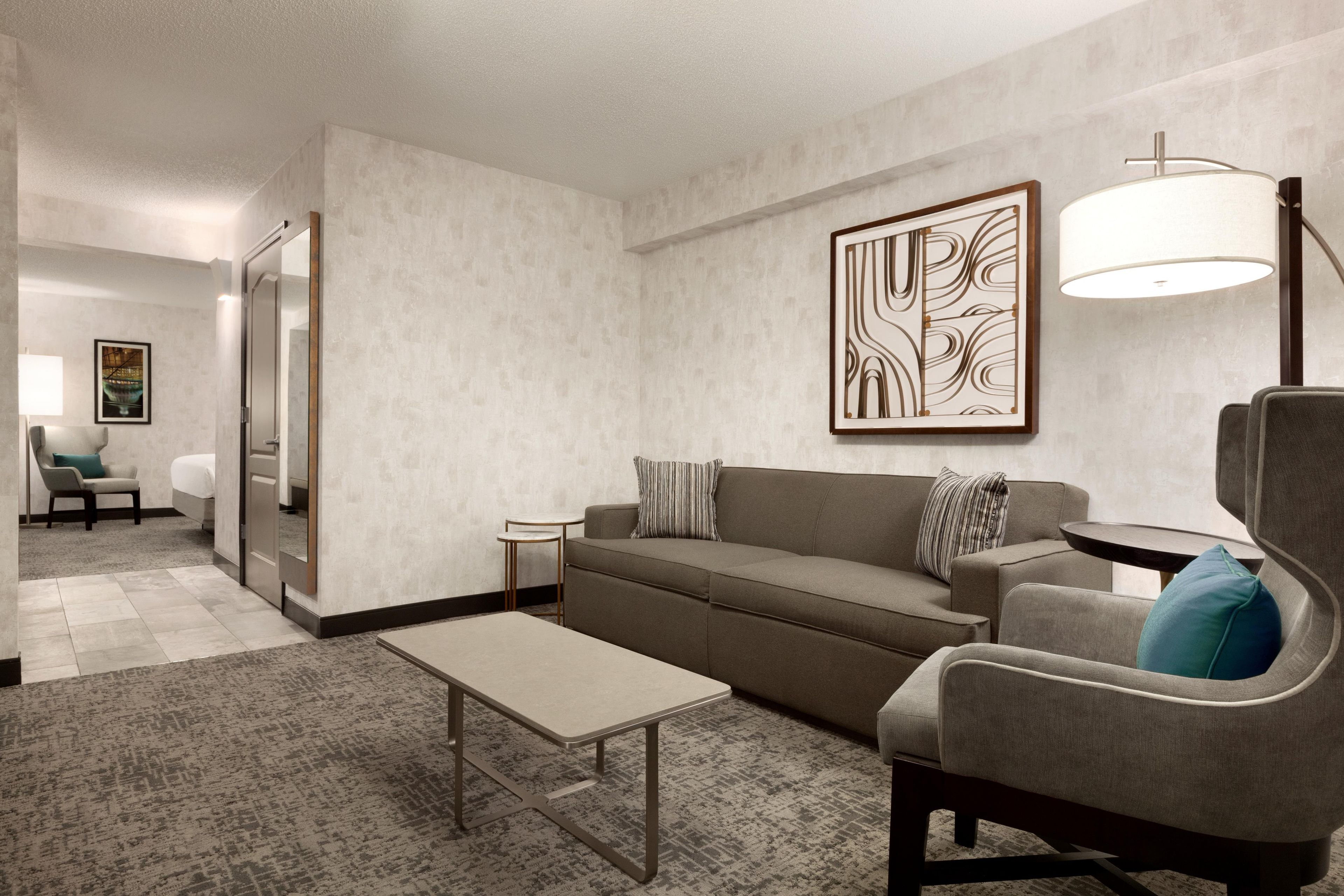 A modern living room with a sofa, armchair, coffee table, and a floor lamp.