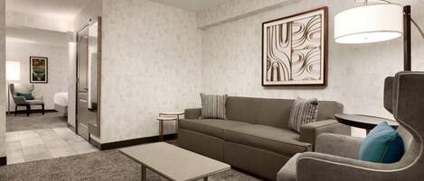 A modern living room with a sofa, armchair, coffee table, and a floor lamp.