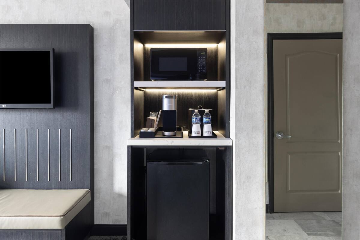 A compact kitchenette with a microwave, coffee maker, and water dispensers.