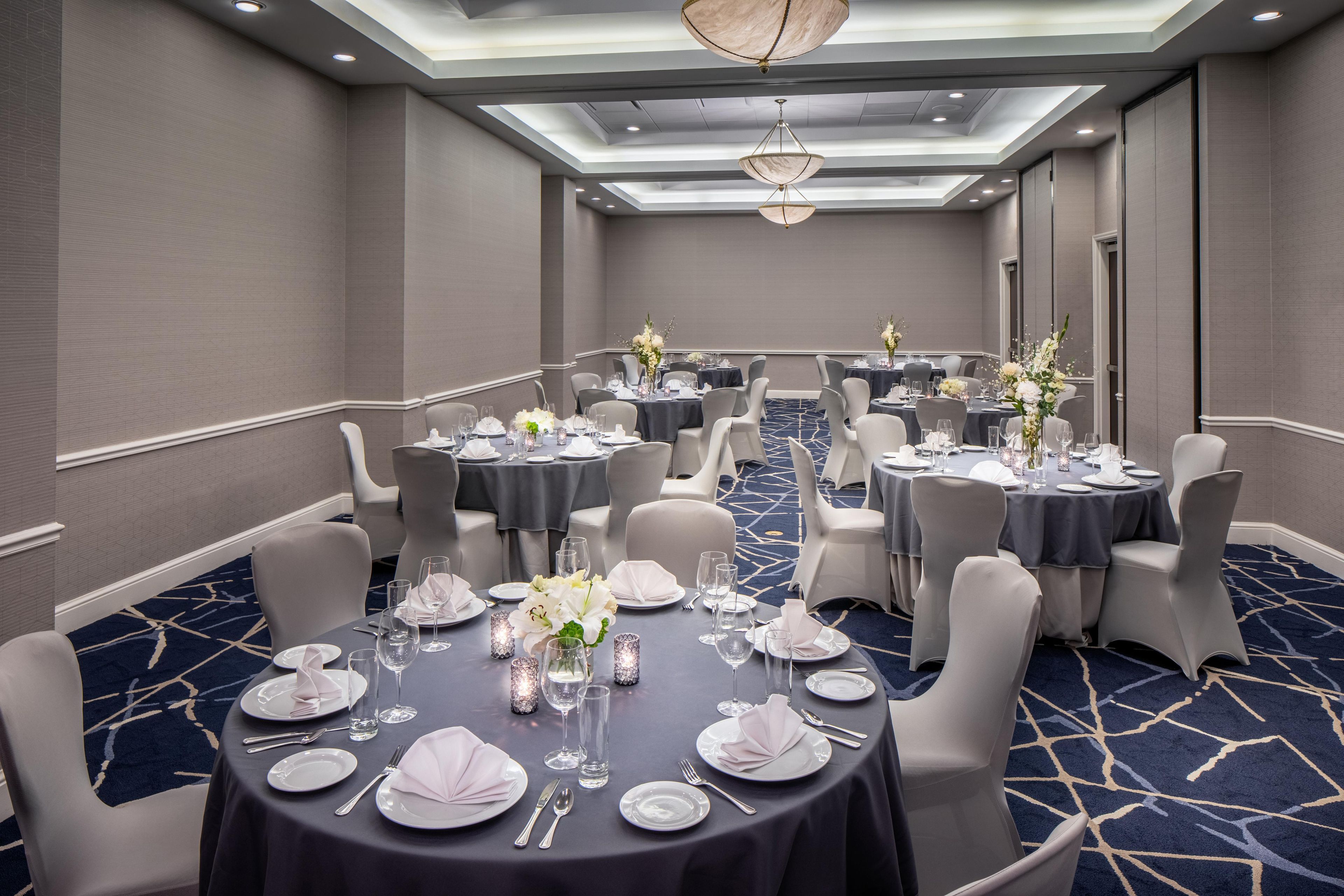 A conference room with round tables, grey chairs, and a blue carpet.