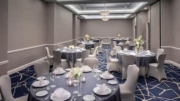 A conference room with round tables, grey chairs, and a blue carpet.