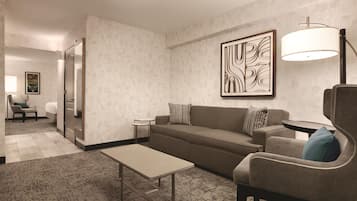 A modern living room with a sofa, armchair, coffee table, and a lamp.