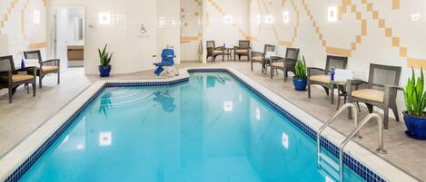 A pool area with a blue pool, lounge chairs, and potted plants.