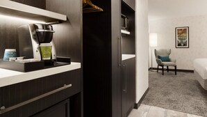 Une chambre d’hôtel équipée d’une kitchenette, d’un lit, d’une chaise et d’un tableau au mur.