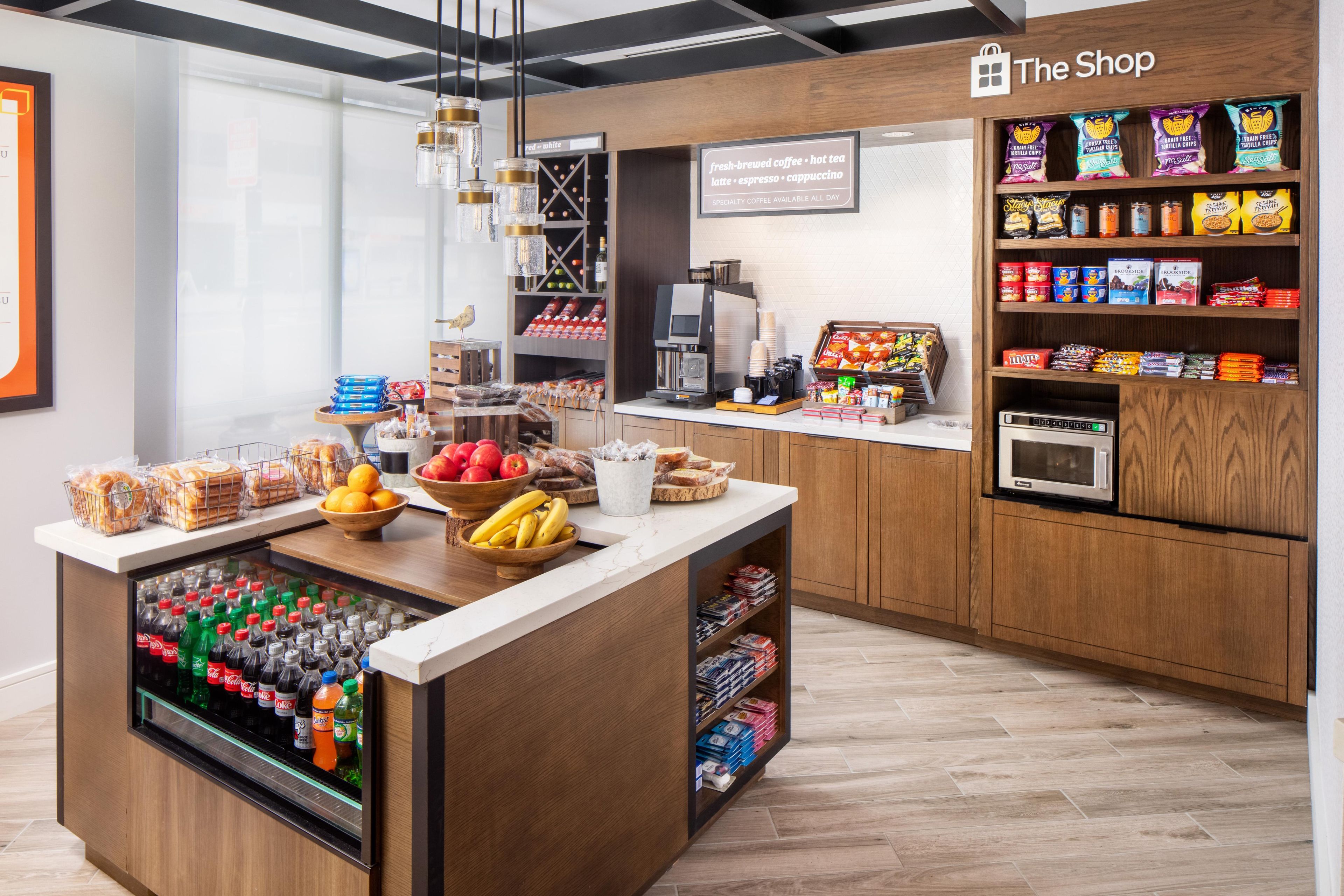 Ein Café-Interieur mit einer Theke, die frische Produkte, eine Kaffeemaschine sowie eine Auswahl an Snacks und Getränken präsentiert.