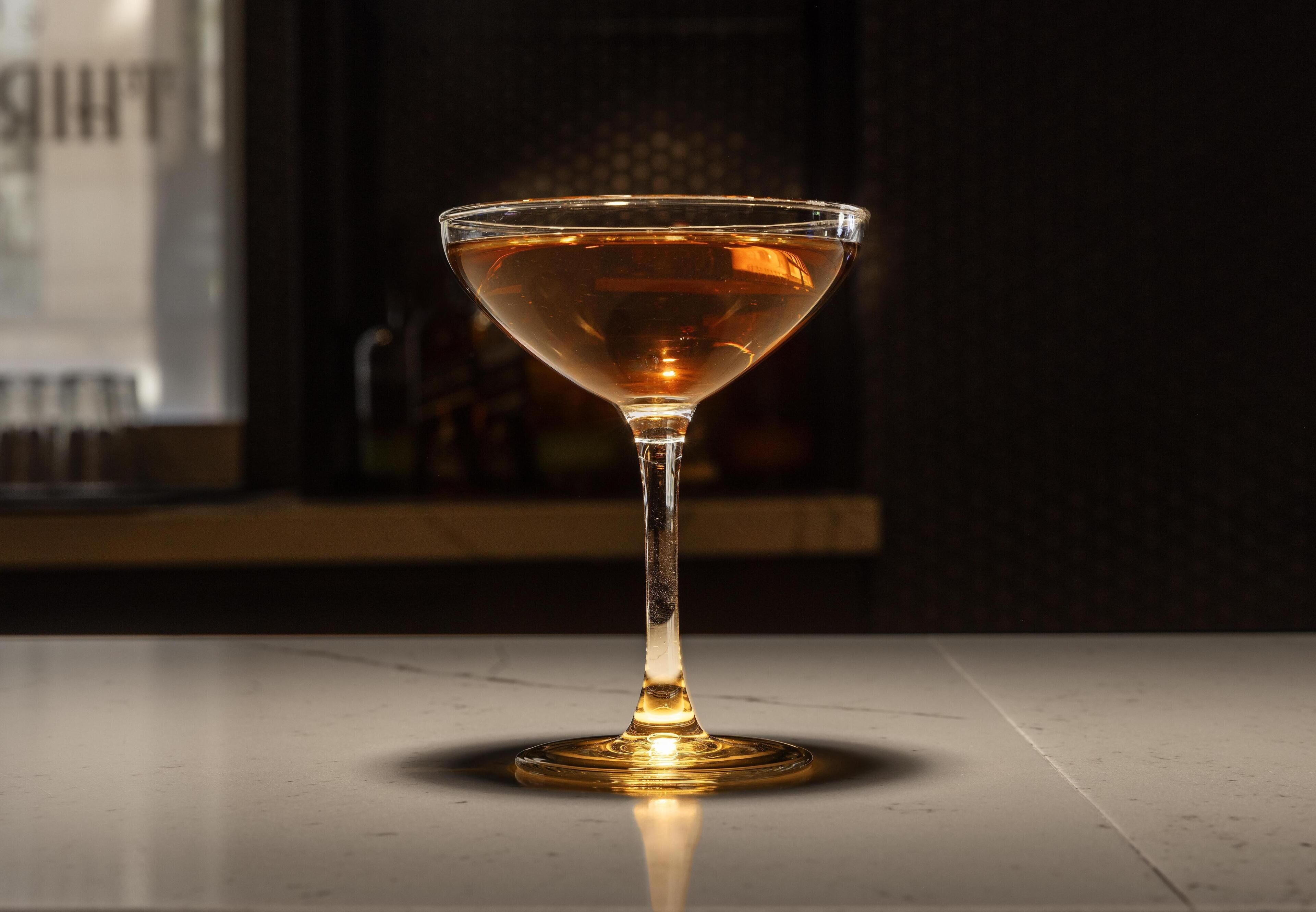 Um copo de martini sobre uma superfície refletora.