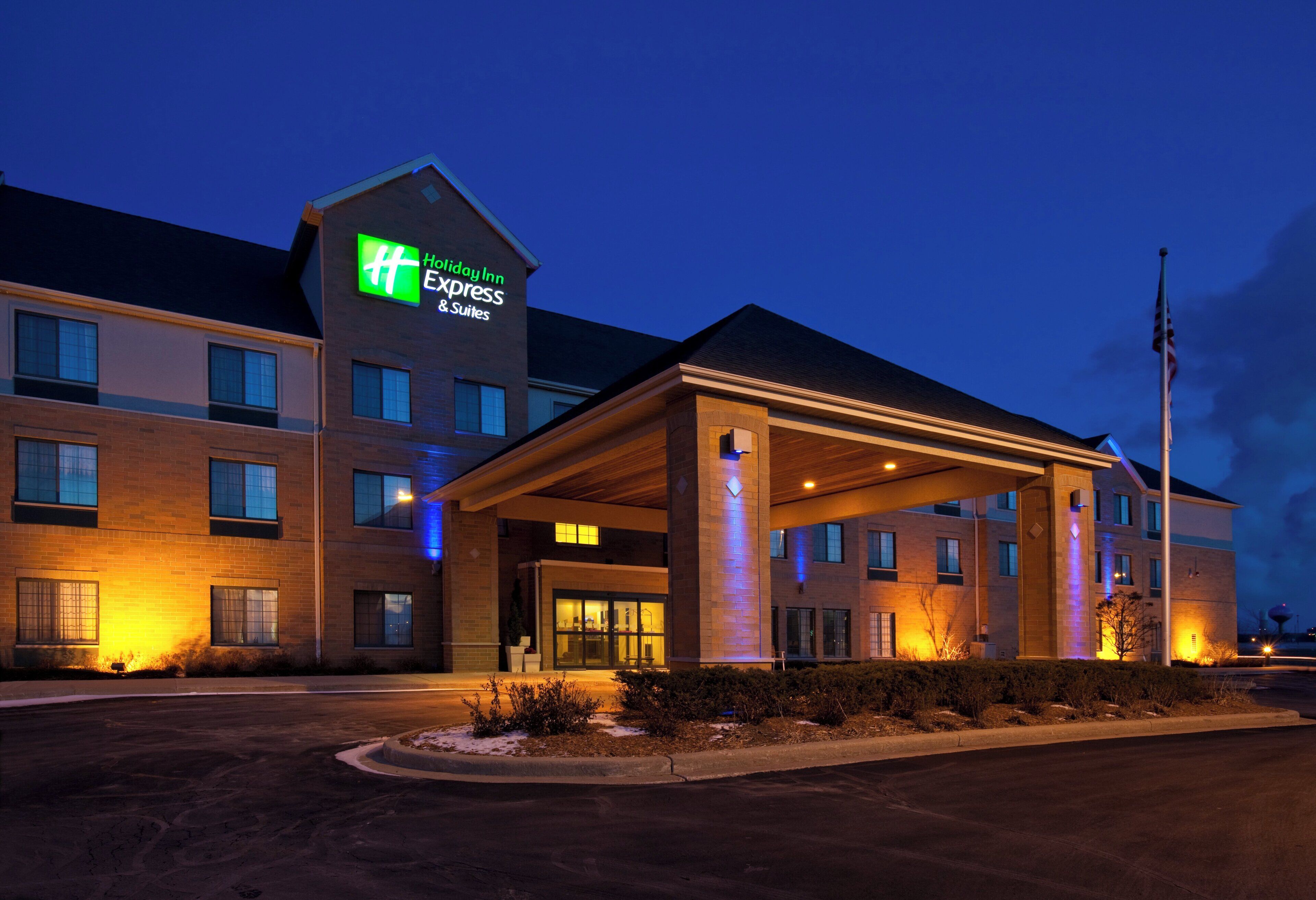 A Holiday Inn Express & Suites hotel with a covered entrance and a flagpole.