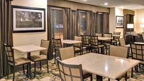 A hotel dining area with multiple tables and chairs, patterned carpet, and framed pictures on the walls. - Holiday Inn Express Hotel & Suites Pleasant Prairie-Kenosha by IHG (Pleasant Prairie)