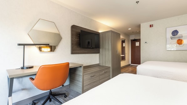 A hotel room with a desk, an orange chair, a bed, a TV, and a painting on the wall. - Holiday Inn Express Hotel & Suites Pleasant Prairie-Kenosha by IHG (Pleasant Prairie)
